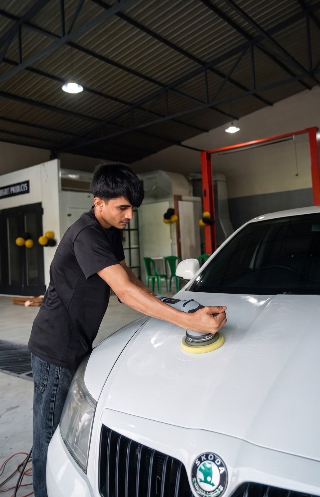 Person polishing the car bonnet inside a workshop